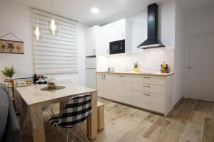 cocina con armarios blancos y mesa de madera en Trauko Flat Optional parking 12day EBI en Bilbao