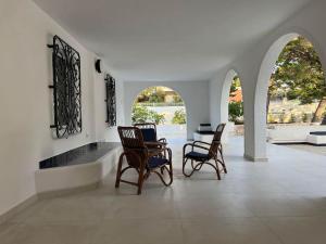 a room with three chairs and a table and windows at Uliveus - Villa Duna fronte mare in Faccia di Trippa