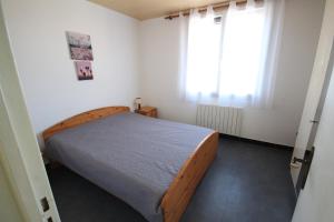 een slaapkamer met een houten bed in een kamer bij Appartement 2 pièces, au 1er étage pour 2 à 4 couchages, proche commerces et 200m plage de PORTIRAGNES PLAGE LXRH9 in Portiragnes