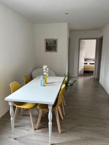 uma mesa de jantar branca com cadeiras amarelas em House Near EPFL/Unil/Renens Gare/Lausanne em Ecublens
