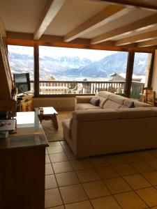 sala de estar con sofá y ventana grande en Vue Mont Blanc et toute la chaîne, en Combloux