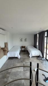 two beds in a room with white walls and windows at La Belle San Isidro Lofts - Loft Violetas in San Isidro