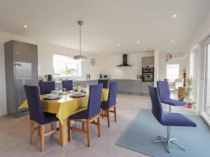 a dining room with a yellow table and blue chairs at Breakish Villa in Breakish