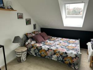 1 Schlafzimmer mit einem Bett mit einer Blumendecke und einem Fenster in der Unterkunft CHAMBRE PRIVÉE dans une maison in Argenteuil