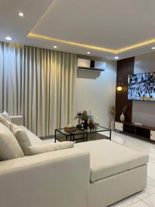 شقة حي العقيق قريبة البوليفارد في الرياض: غرفة معيشة مع أريكة بيضاء وتلفزيون