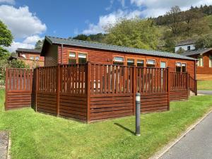 a wooden cabin with a fence in the grass at Mon Reve in Windermere