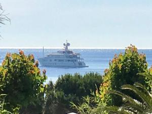 a yacht in the water with trees in the foreground at MOBIL HOME PLAGE DE PAMPELONNE SUR UN TRES BEL EMPLACEMENT SURPLOMBANT LA BAIE DE PAMPELONNE in Saint-Tropez
