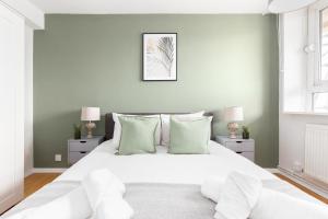a white bedroom with a large white bed with green pillows at The Bermondsey Apartments in London