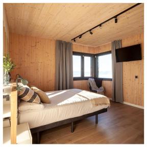 - une chambre avec un grand lit dans une pièce dotée de murs en bois dans l'établissement EAGLE'S NEST, à Castellnou de Bages