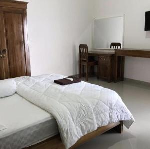 um quarto com uma cama, uma secretária e uma cadeira em Omah Joglo Pantai Pulau Merah em Pasanggaran