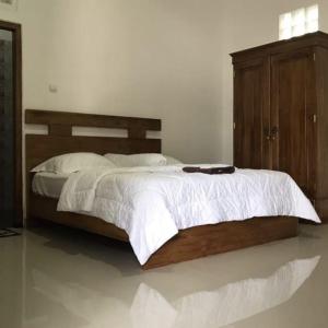 um quarto com uma cama grande e uma cabeceira em madeira em Omah Joglo Pantai Pulau Merah em Pasanggaran