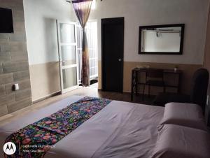 - une chambre avec un lit et un miroir mural dans l'établissement Hotel Casa Tepic, à Tepic