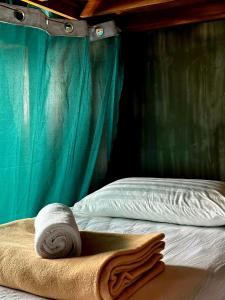 a bed with a rolled up towel on it at El Lobo Hostel in General Luna