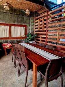 uma sala de jantar com uma longa mesa de madeira e cadeiras em El Lobo Hostel em General Luna
