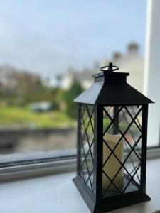 a black lantern sitting on a table in front of a window at Princetown Guesthouse in Bangor