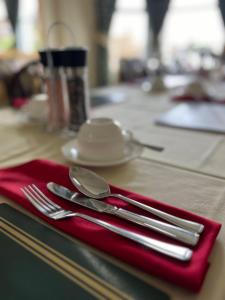 una servilleta roja con utensilios de plata sobre una mesa en Princetown Guesthouse en Bangor