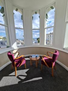 2 sillas y una mesa en una habitación con ventanas en Metropole Hotel, en Torquay
