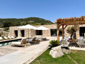 eine Terrasse mit Stühlen und Sonnenschirmen neben einem Pool in der Unterkunft Villa Grenadier by Intendance Excellency in Cirendinu