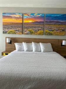 a bedroom with a bed with three paintings on the wall at Days Inn by Wyndham Copperas Cove in Copperas Cove