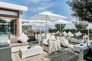 d'une terrasse avec des meubles blancs et des parasols blancs. dans l'établissement Rouge Hotel International, à Milano Marittima