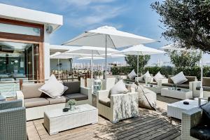 un patio con muebles blancos y sombrillas blancas en Rouge Hotel International en Milano Marittima