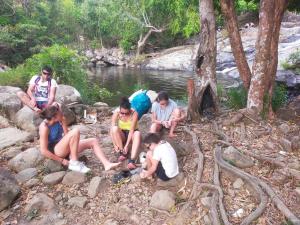 Eine Gruppe von Menschen, die auf Felsen in der Nähe eines Flusses sitzen in der Unterkunft Lak village in Lien Son