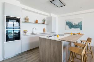 a kitchen with white cabinets and a wooden island with stools at Cliff Edge in Newquay