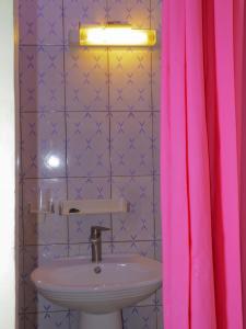 a bathroom with a sink and a pink shower curtain at La Case a Mamy in Nianing