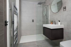 a bathroom with a shower with a sink and a mirror at Cliff Edge in Newquay