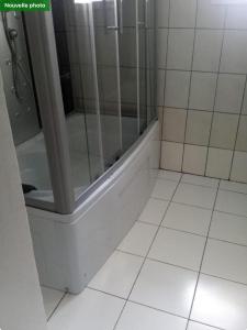 baño con ducha y suelo de baldosa blanca. en Villa SPIROU en Ivato