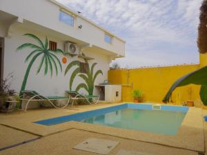 a swimming pool in front of a house with a palm tree mural at La Case a Mamy in Nianing