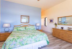 a bedroom with a bed and two dressers and a mirror at 1623 Ridge in Kahana