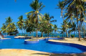 - une piscine bordée de palmiers sur la plage dans l'établissement Lux Suites Lamera Beachfront Apartments, à Shanzu