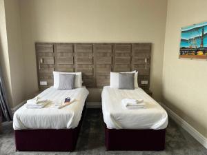 2 camas en una habitación de hotel con sábanas blancas en Queens Hotel, en Blackpool