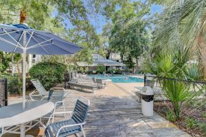 une terrasse avec une table, des chaises et une piscine dans l'établissement Ocean Breeze 27, à Île de Hilton-Head