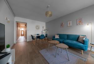 a living room with a blue couch and a table at L'Eugène - Maison 3 chambres in Vichy