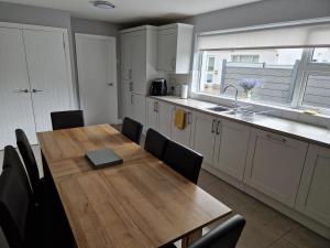 a kitchen with a wooden table and black chairs at Woodhill Lodge Irvinestown, Necarne in Irvinestown