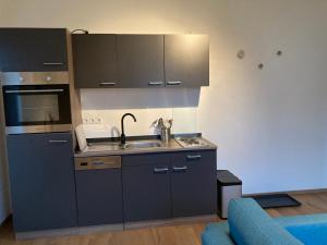 a kitchen with gray cabinets and a sink and a blue couch at Ferienwohnung Am Hochkelberg in Bereborn