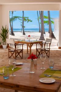 a wooden table with glasses and flowers on a beach at Diamonds Mapenzi Beach in Kiwengwa