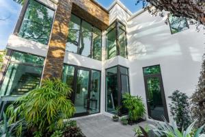 a large white house with glass windows and plants at Villa Celine in Fort Lauderdale