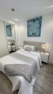 una camera bianca con un grande letto e uno specchio di Madrid House Boutique , Aeropuerto , Ifema a Madrid