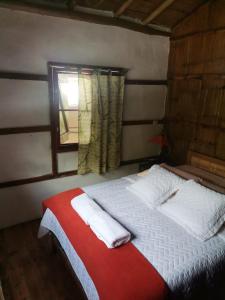 1 dormitorio con 1 cama con sábanas blancas y ventana en Cabañas Bambu Mindo, en Mindo
