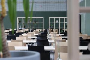Sportschule Wedau في دويسبورغ: غرفة فارغة فيها طاولات وكراسي وجدار أخضر