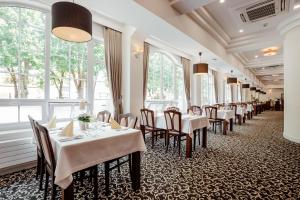 un restaurante con mesas y sillas blancas y ventanas en Hotel pod Zámkom, en Bojnice