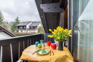 a table with a vase of yellow flowers on a balcony at Aixpress Apartment in Bad Herrenalb