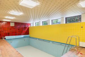 a swimming pool with yellow and blue tiles at Aixpress Apartment in Bad Herrenalb