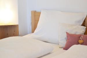 uma cama com lençóis brancos e almofadas em Tholer Ferienwohnung 2 em Lagundo