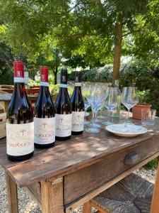 four bottles of wine on a wooden table with glasses at La Vineria di San Mattia in Verona