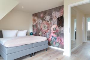 1 dormitorio con 1 cama con pared de flores en Family Hüs, en Westerland