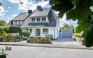 uma casa branca com um telhado cinzento e uma entrada em Hedigen Hüs em Westerland